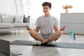 Asian man meditating in lotus position on mat with pc Royalty Free Stock Photo