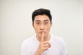 Asian man over  white wall showing a sign of silence gesture putting finger in mouth Royalty Free Stock Photo