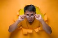 Asian man poses over torn paper hole with eyeglasses seriously looking at the camera Royalty Free Stock Photo