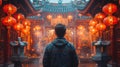 Asian man prays at Man Mo Temple in Hong Kong with lamps and incense coils hanging on the ceiling Royalty Free Stock Photo