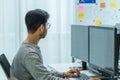 Asian man prompt engineer develop coding app with software data sitting in front of computer monitor at office Royalty Free Stock Photo