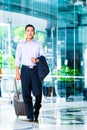 Asian man pulling suitcase in hotel lobby