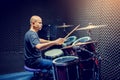 Asian man put black t-shirt to playing the drum set with wooden drumsticks in music room Royalty Free Stock Photo