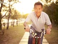 Asian man riding bike outdoors at sunset