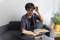 Asian man rubbing eye with tired expression after long period reading book. Royalty Free Stock Photo