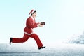 Asian man in Santa costume holding gift box while running Royalty Free Stock Photo