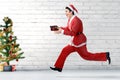 Asian man in Santa costume running while holding the gift box with a Christmas tree Royalty Free Stock Photo