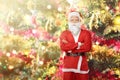 Asian man in Santa costume standing with a decorated Christmas tree with colorful lights Royalty Free Stock Photo