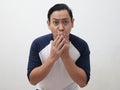 Asian man shocked and worried to see something bad, covering his mouth with hands and big eyes open, over grey Royalty Free Stock Photo