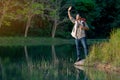 Asian man show action of greeting by wave hands and look forward to the lake during travel and camping in national park