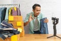 Asian man showing okay and using smart mobile phone taking live selling pants jeans online