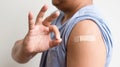 Asian man shows plaster on her shoulder after being vaccinated against Covid-19. Coronavirus vaccination campaign concept Royalty Free Stock Photo
