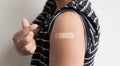 Asian man shows plaster on her shoulder after being vaccinated against Covid-19. Coronavirus vaccination campaign concept Royalty Free Stock Photo