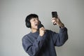 Asian man singing listening to music on smartphone wearing headphones. Royalty Free Stock Photo