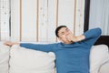 Asian man siting on sofa and yawn when finish moving box to new house with tired feeling