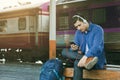 Asian man sitting on bench listening to music at train station w Royalty Free Stock Photo