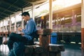 Asian man sitting on bench and using smartphone with waiting train. Royalty Free Stock Photo