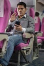 Asian man sitting comfortably in business class Businessman working on a laptop computer and smartphone during an airplane flight Royalty Free Stock Photo