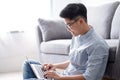 Asian man sitting on the floor and working on a computer laptop at home with copy space Royalty Free Stock Photo