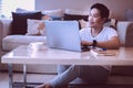 Asian man sitting on floor working on laptop at home. Royalty Free Stock Photo