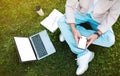 Asian man sitting on grass while using phone and laptop Royalty Free Stock Photo