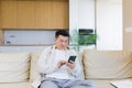 Asian man sitting at home, using a smartphone, serious typing a message on the phone Royalty Free Stock Photo