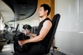 Asian man sitting on machine curling dumbbells in gym Royalty Free Stock Photo