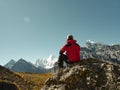 Asian man sitting on top of rock looking at view with Mount Yangmaiyong or Jampayang in Tibetan in the distance in Yading, China Royalty Free Stock Photo