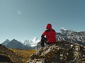 Asian man sitting on top of rock looking at view with Mount Yangmaiyong or Jampayang in Tibetan in the distance in Yading, China Royalty Free Stock Photo