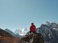 Asian man sitting on top of rock looking at view with Mount Yangmaiyong or Jampayang in Tibetan in the distance in Yading, China Royalty Free Stock Photo