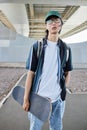 Asian man with skateboard posing outdoors Royalty Free Stock Photo