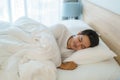 Asian man are sleeping and having good dreams in white blanket in the morning. Rest after work tiring in bedroom at home Royalty Free Stock Photo