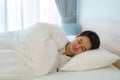 Asian man are sleeping and having good dreams in white blanket in the morning. Rest after work tiring in bedroom at home Royalty Free Stock Photo