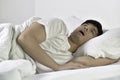 Asian man sleeping and snoring loudly lying in the bed