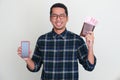 Asian man smiling confident while showing blank handphone screen and wallet full of money Royalty Free Stock Photo