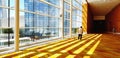 The Asian man standing back in the light pattern and shadow line on the yellow rug that shines from the outside of the building