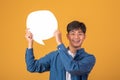 Asian man standing with a blank image of paper On orange background