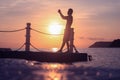 Asian man standing on floating pier at sunrise , Silhouette body of asian people early morning on the beach Royalty Free Stock Photo
