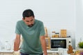 Asian man standing with his arms on the table in the kitchen preparing breakfast, thinking what to cook. in the morning of the Royalty Free Stock Photo