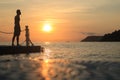 Asian man standing and jumping on floating pier at sunrise , Silhouette body of asian people early morning on the beach Royalty Free Stock Photo