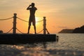 Asian man standing and jumping on floating pier at sunrise , Silhouette body of asian people early morning on the beach Royalty Free Stock Photo