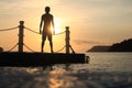 Asian man standing and jumping on floating pier at sunrise , Silhouette body of asian people early morning on the beach Royalty Free Stock Photo