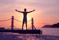 Asian man standing and jumping on floating pier at sunrise , Silhouette body of asian people early morning on the beach Royalty Free Stock Photo