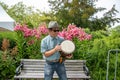 An Asian man standing and playing the djembe.