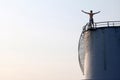 Asian man standing on the top of a large white Industrial tanks for petrol and oil Royalty Free Stock Photo