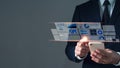 An Asian man in a suit with his left hand holding a mobile phone. His right hand pointing at a hologram showing business icons and Royalty Free Stock Photo