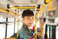 Asian man taking public transport, standing inside bus. Royalty Free Stock Photo