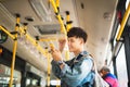 Asian man taking public transport, standing inside bus. Royalty Free Stock Photo