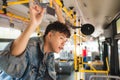 Asian man taking public transport, standing inside bus. Royalty Free Stock Photo