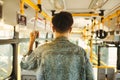 Asian man taking public transport, standing inside bus. Royalty Free Stock Photo